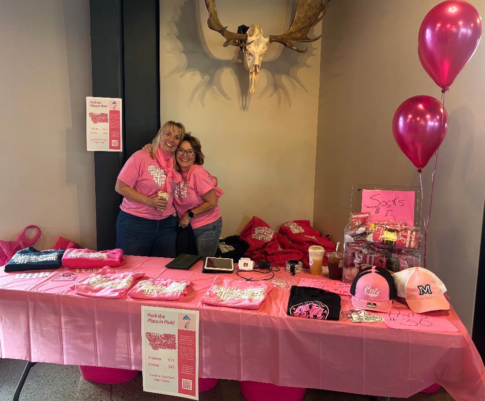 Ladies hugging at a Pack the Place in pink booth