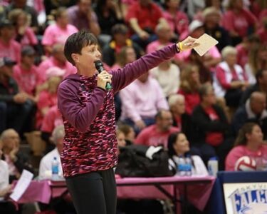 Woman pointing with microphone at a sporting event